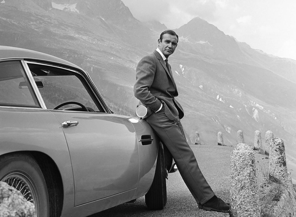 James bond leaning against car